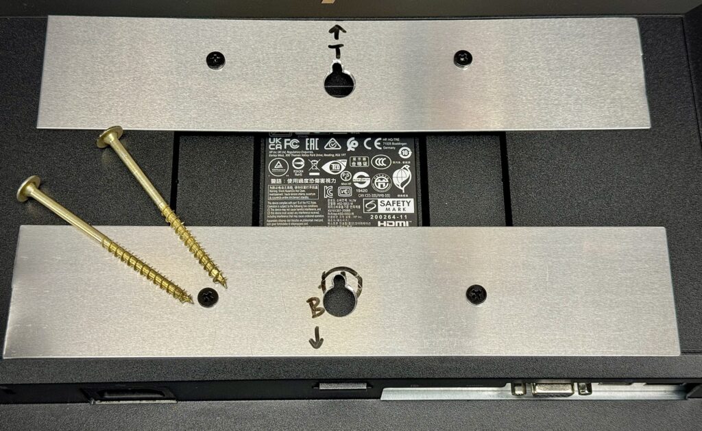 Monitor with aluminum brackets attached and screws for mounting to the wall.